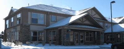 Two-story stone and siding building with gabled roofs, in snow