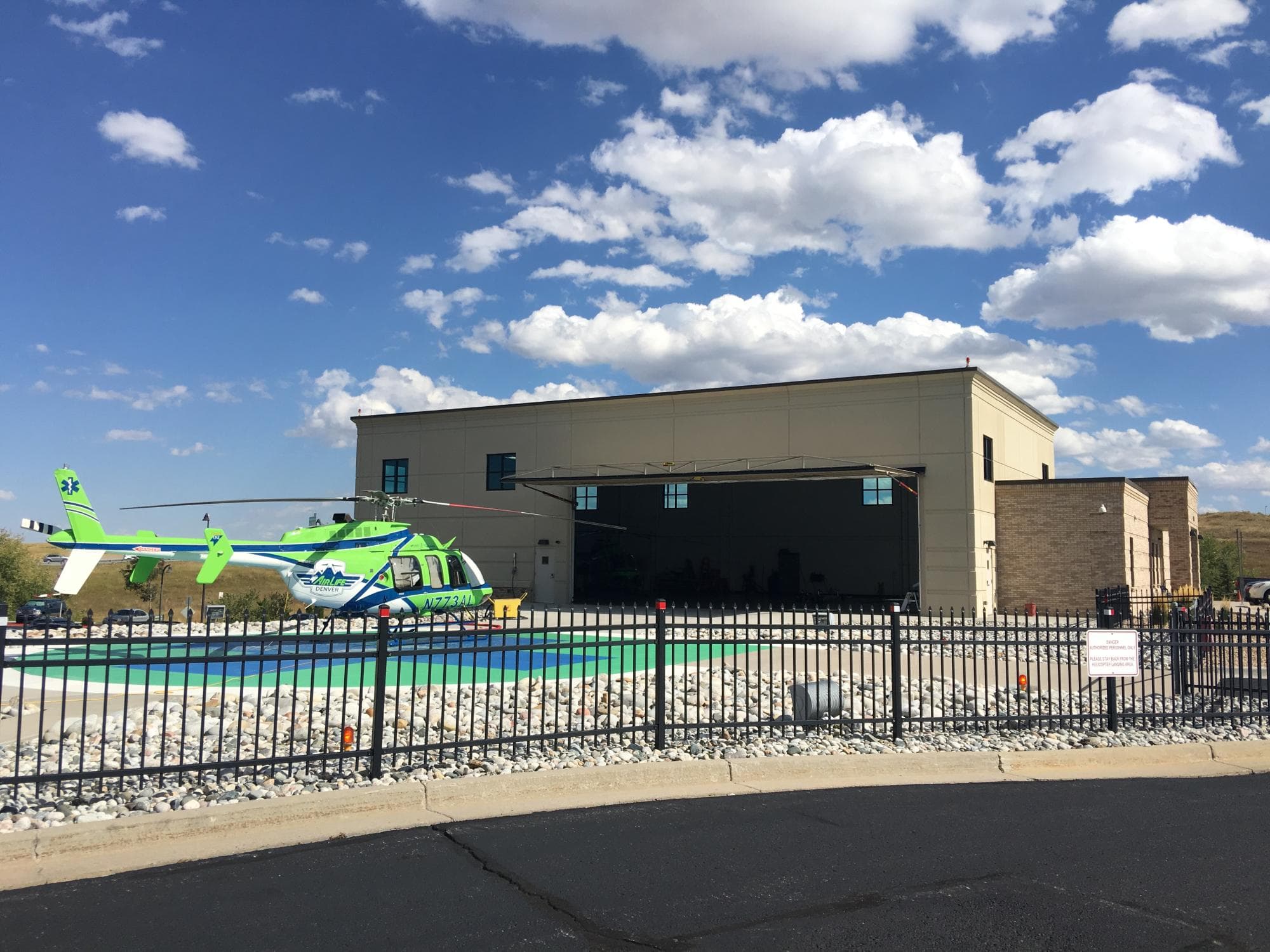 Air Life helicopter hangar at Sky Ridge Medical Center, with a helicopter on the pad under a blue sky